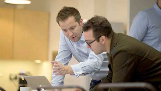 Two employees discussing work reviewing a laptop